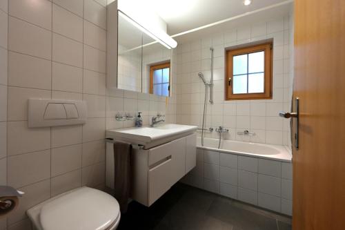 a bathroom with a toilet and a sink and a tub at Chesa Igna in Arosa