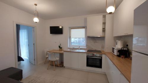 una cocina con armarios blancos, una mesa y una barra en Cora Apartment, en Baia Mare