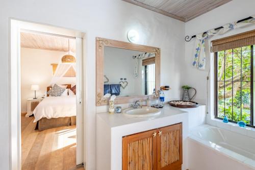 a bathroom with a sink and a mirror and a bed at Tidal Retreat in Plettenberg Bay