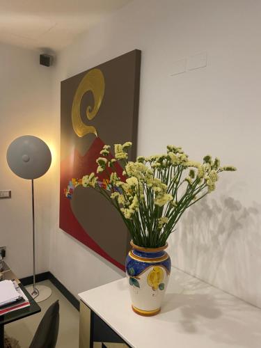 un vaso pieno di fiori seduto su un tavolo di Hotel Plebiscito Aparthotel a Napoli