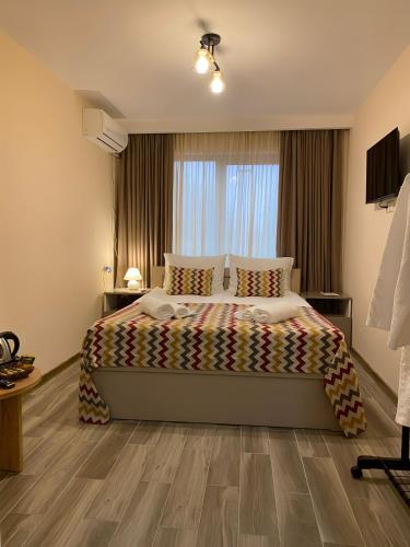 a bedroom with a bed and a large window at Kera Rooms in Tʼelavi