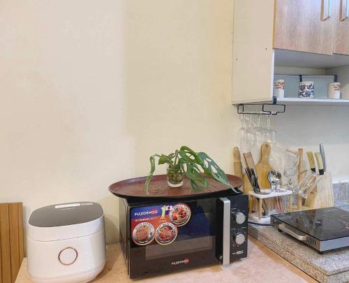 a microwave on a counter with a plant on top of it at Cabin in Urban - Urban Deca Homes - Manila in Manila