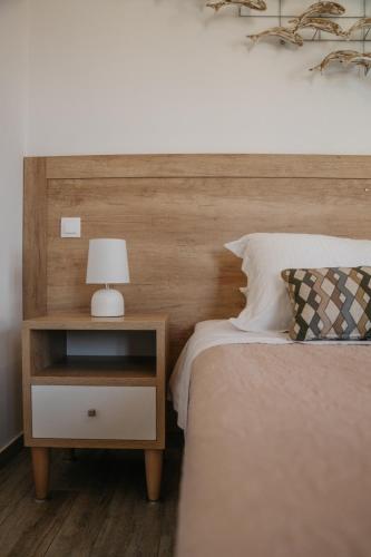 a bed with a wooden headboard and a night stand with a lamp at Arhontou in Apollonia