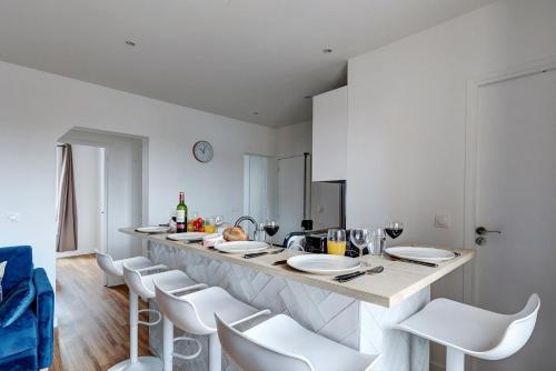 a white kitchen with a counter with white stools at 869-Suite Bleuet - Superb Apartment in Montreuil