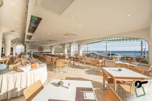 un restaurante con mesas y sillas y vistas al océano en HOTIDAY Hotel Leuca, en Leuca