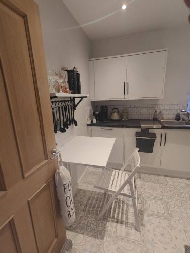 a kitchen with white cabinets and a table and a chair at Central Caversham Reading one bed flat in Reading