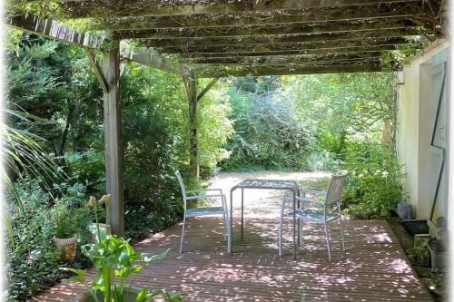 een tafel en stoelen op een patio onder een pergola bij **** Les Petites Mares **** in La Mothe-Achard