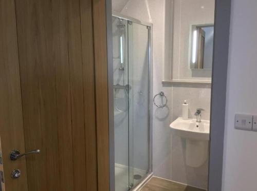 uma casa de banho com uma cabina de duche em vidro e um lavatório. em Hunters Lodge em Barnstaple
