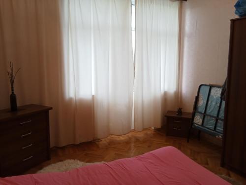 Квартира в престижном районе Баку في باكو: غرفة نوم مع ستائر بيضاء وخزانة ومرآة