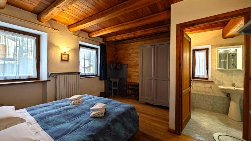 1 dormitorio con 1 cama y baño con lavamanos en Hostdomus - La Posta apartment, en Pragelato