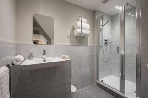 a white bathroom with a shower and a sink at Cosy, Bright, 1 Bed Flat in Brentwood