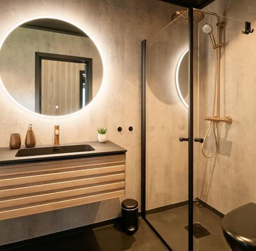 a bathroom with a sink and a shower with a mirror at Koie Deluxe II in Stranda