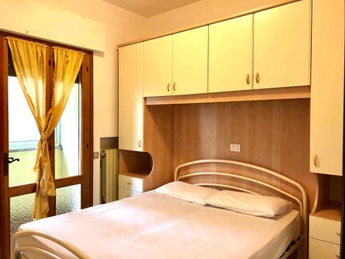 Schlafzimmer mit einem Bett, einem Fenster und Schränken in der Unterkunft Holiday home in Rosolina Mare 24967 in Rosolina Mare