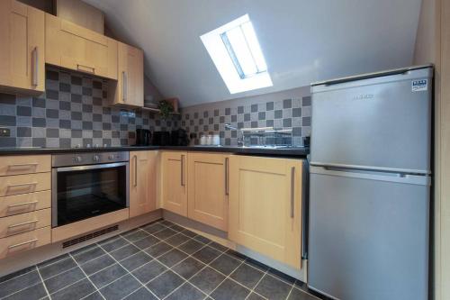 eine Küche mit Holzschränken und einem weißen Kühlschrank in der Unterkunft The Nest - cosy and quiet 1 bed central in Buckinghamshire