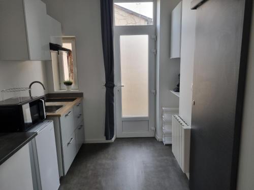 une cuisine avec des armoires blanches et une fenêtre dans l'établissement La Fourmi, à Soissons