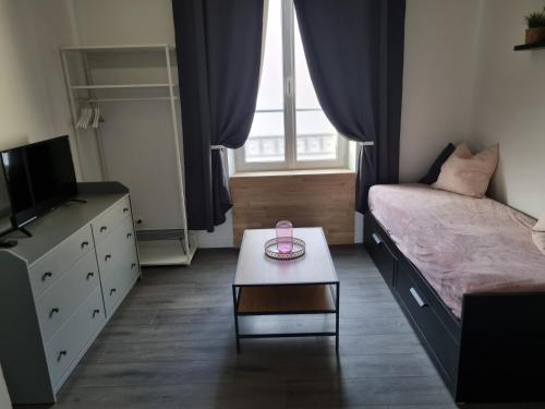 a bedroom with a bed and a table and a window at La Fourmi in Soissons