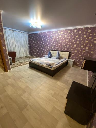 1 dormitorio con cama y pared púrpura en 1-x Квартира в центре города по доступной цене, en Rudny