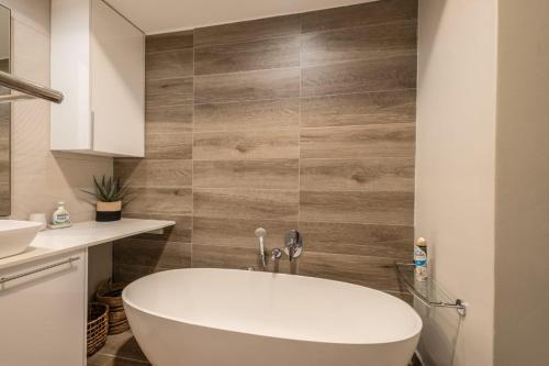 a bathroom with a white tub and a wooden wall at Menlyn apartment with ensuit Regency Hotel in Pretoria