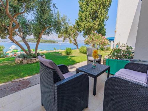 eine Terrasse mit Stühlen und einem Tisch mit Blick auf das Wasser in der Unterkunft Lumbarda Resort Apartments in Lumbarda