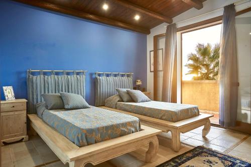 a bedroom with two beds and a blue wall at Villa Claudia in Castelvetrano Selinunte