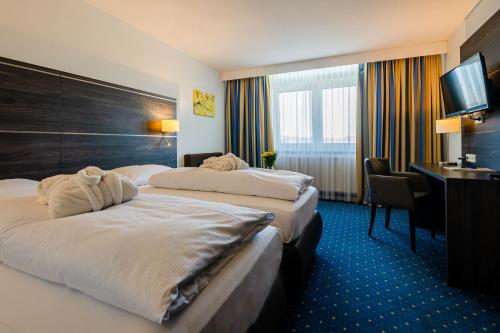 ロイトリンゲンにあるHotel Fortuna Reutlingen-Tübingenのベッド2台とデスクが備わるホテルルームです。