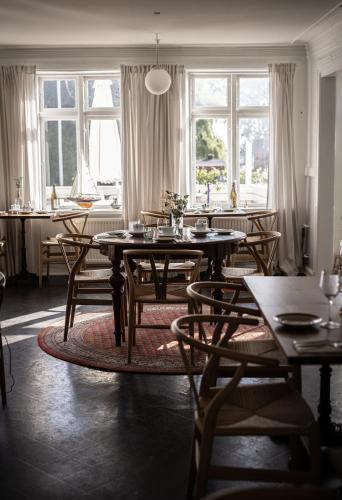 a dining room with tables and chairs and windows at Arnfeldt Hotel & Restaurant in Ærøskøbing