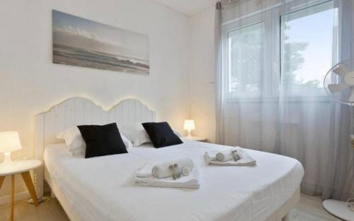 een slaapkamer met een wit bed en handdoeken bij Appartement lumineux à Biarritz in Biarritz