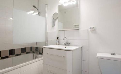 een witte badkamer met een wastafel en een bad bij Appartement lumineux à Biarritz in Biarritz
