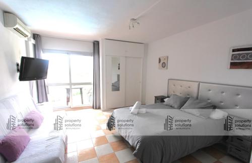Un dormitorio con una cama y un televisor. en 427 Estudio en Júpiter Apartamentos - Vista a la piscina, el mar y las montaña, en Benalmádena