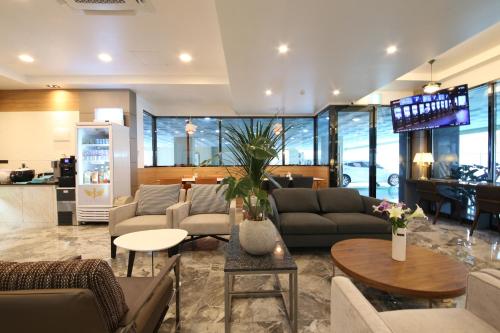a living room with couches and tables and a kitchen at Hotel J's in Gumi