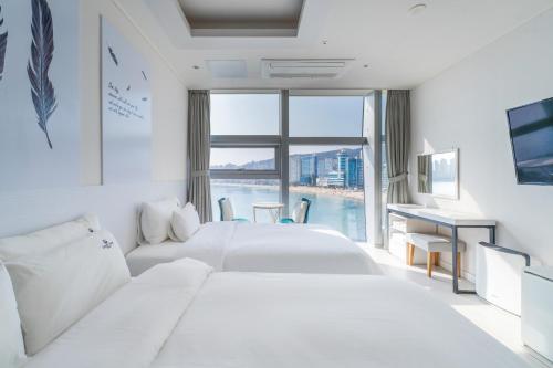 a hotel room with two white beds and a desk at Oceanstay Hotel in Busan