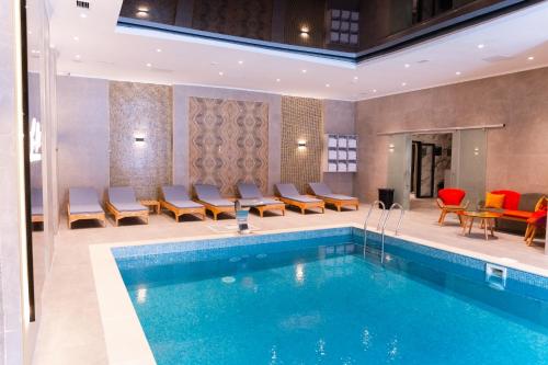a pool in a hotel room with chairs and tables at Park Dedeman Almaty in Almaty