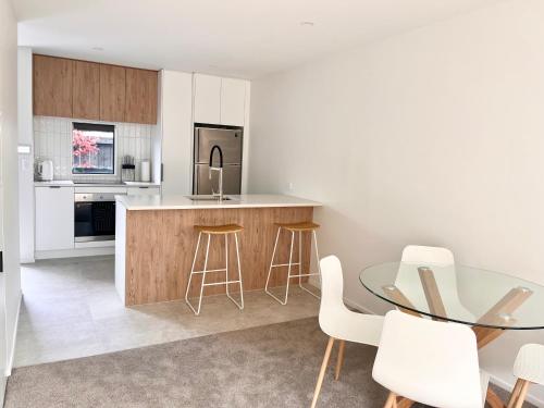 a kitchen with a glass table and white chairs at Urban Locale in Christchurch