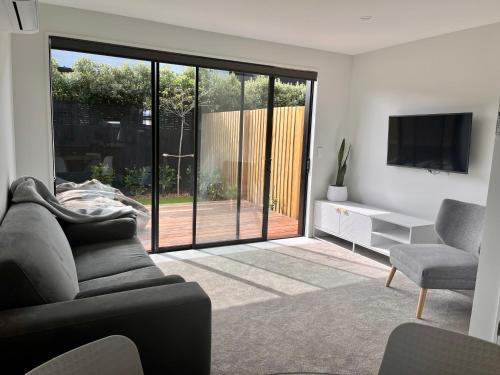 a living room with a couch and a tv and a sliding glass door at Urban Locale in Christchurch