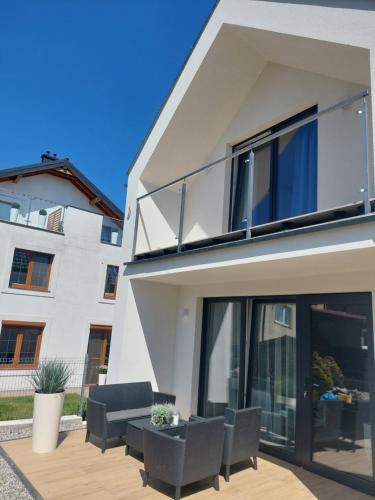 a white house with black chairs and a balcony at Domki Balticana in Władysławowo