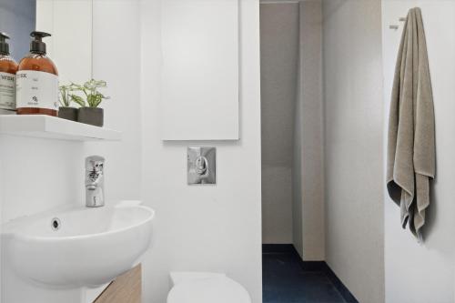ein weißes Bad mit einem Waschbecken und einem WC in der Unterkunft Come Stay 2BR Lejlighed nær Centrum & Togstation in Aalborg