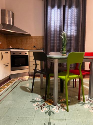a kitchen with a table and two green chairs at Sicilia Vacation in Trapani