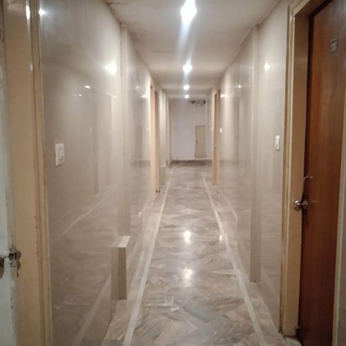 an empty hallway with marble flooring and a hallway with a door at Hotel Cozy Residency in Jabalpur