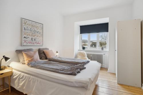 ein weißes Schlafzimmer mit einem Bett und einem Fenster in der Unterkunft Come Stay 2BR Lejlighed nær Centrum & Togstation in Aalborg