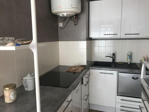 une petite cuisine avec des armoires blanches et un évier dans l'établissement Appartement T2 Arcachon centre, commerces et plage à pied, à Arcachon