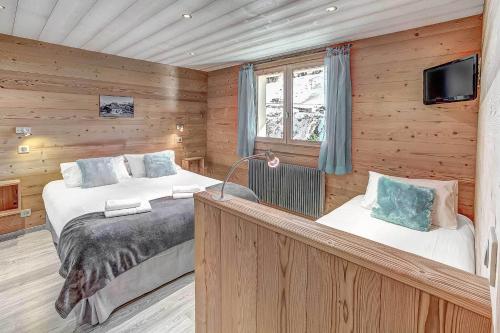 a bedroom with two beds and a television in it at Les Congères in Le Grand-Bornand