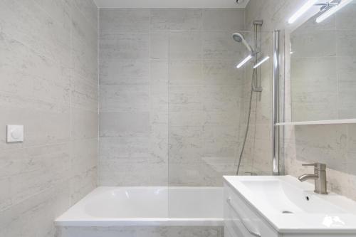 uma casa de banho branca com uma banheira e um lavatório em MBA - Splendide Appart - Bobillot - Proche Vincennes em Montreuil