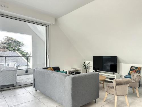 un salon avec un canapé et une télévision dans l'établissement Le 121 - Appartement 201, à Quiberon
