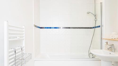 een witte badkamer met een douche en een wastafel bij Stunning flat near the Lake in Gosport