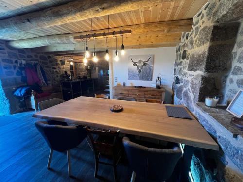 a wooden table in a room with a stone wall at Buron Cœur d’Aubrac in Marchastel