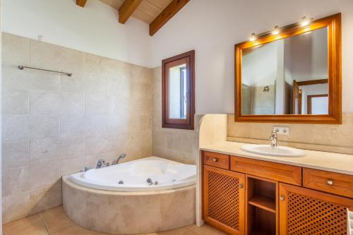 een badkamer met een bad, een wastafel en een spiegel bij Villa Guillona in Alcudia