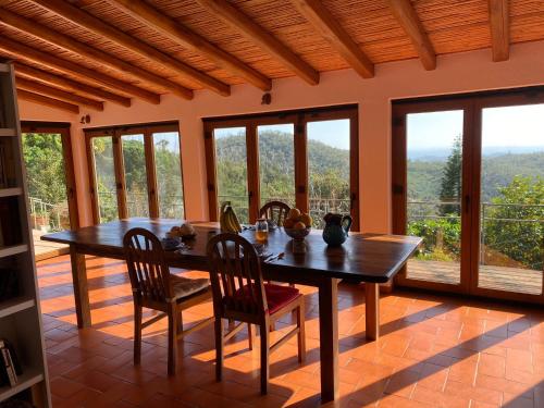 uma sala de jantar com mesa, cadeiras e janelas em Corgos, Flores em Monchique