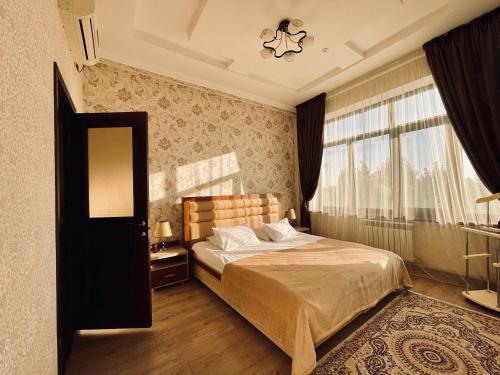 sypialnia z łóżkiem i dużym oknem w obiekcie Dostyk w Kyzyłordzie