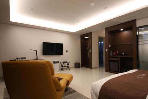 une chambre d'hôtel avec une chaise jaune et une télévision dans l'établissement Hotel J's, à Gumi