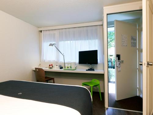 Schlafzimmer mit einem Bett und einem Schreibtisch mit einem Computer in der Unterkunft Hotel Campanile Besançon Nord Ecole Valentin in Besançon